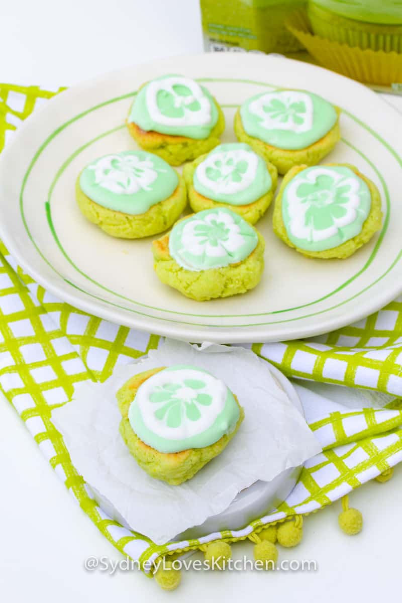 six key lime cookies on a plate and one key lime cookie on a smaller plate in front of larger plate of cookies
