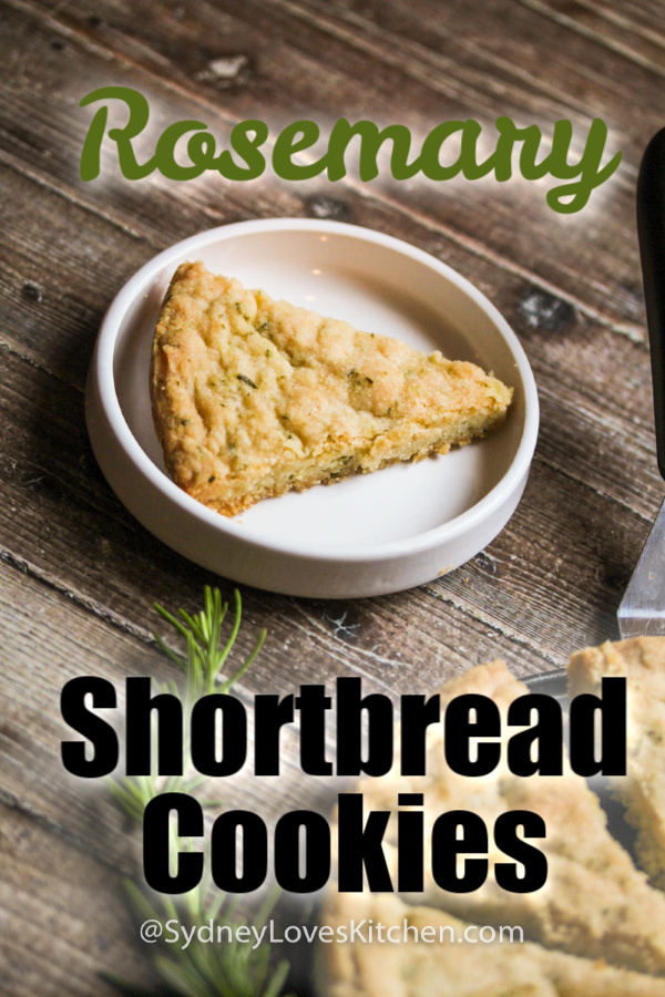 rosemary shortbread cookie slice on a white plate with a rosemary sprig in the foreground