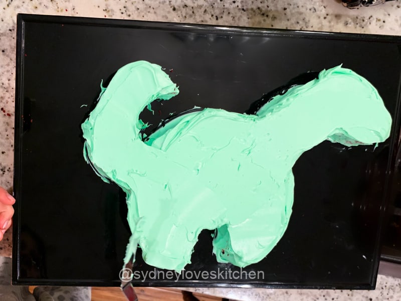 Green frosted kids dinosaur cake before decoration