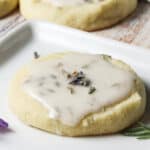 Lavender cookie with lemon frosting on a white plate.