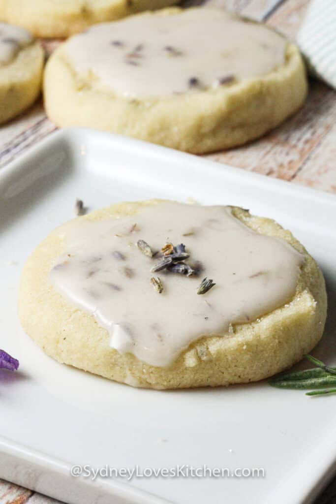 Lavender cookie with lemon frosting on a white plate.