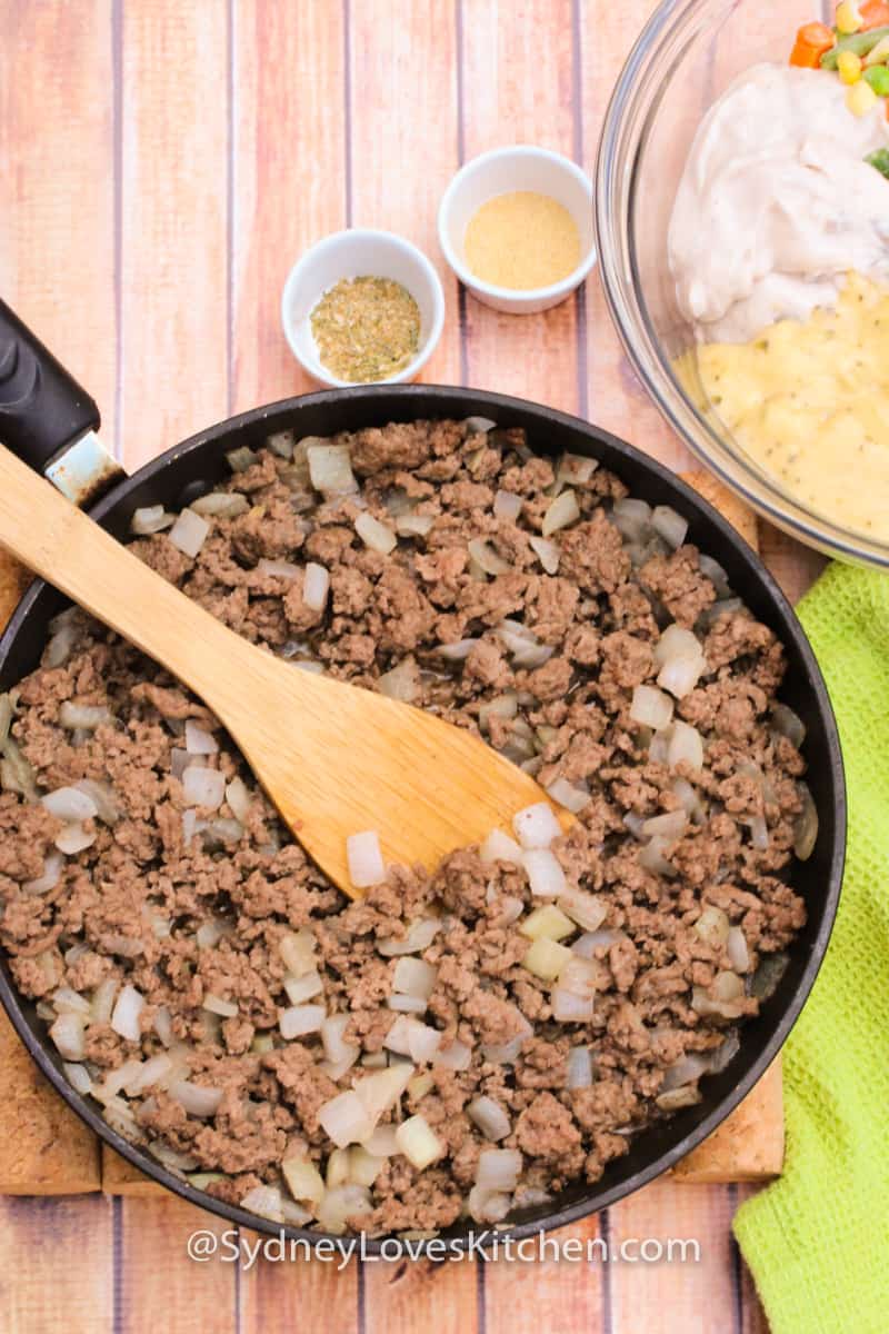 Tater tot casserole ingredients with ground beef in a frying pan