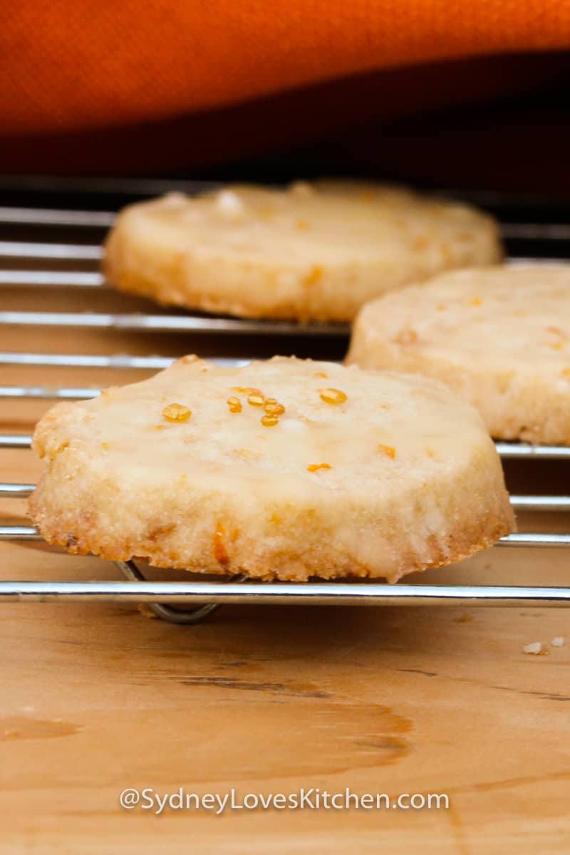 close up of three orange cookies on rack