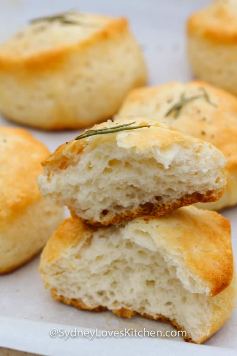 Close up of cooked rosemary biscuits stacked on top of each other.